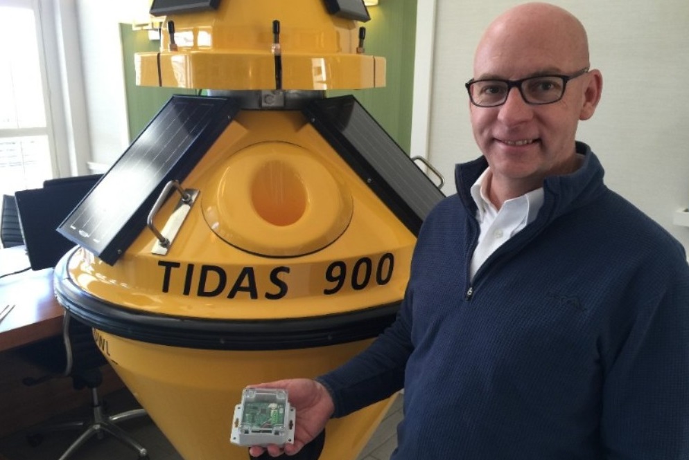 Don Wire is shown standing next to a Tidas 900 buoy while holding a SeaView Systems SVS-603 wave sensor.